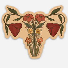 Load image into Gallery viewer, Detailed vinyl matte sticker depicting a uterus anatomy design adorned with orange wildflowers—symbolizing feminine resilience and botanical grace.