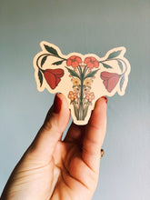 Load image into Gallery viewer, Detailed vinyl matte sticker depicting a uterus anatomy design adorned with orange wildflowers—symbolizing feminine resilience and botanical grace.