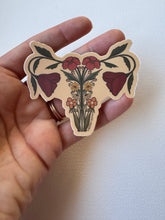 Load image into Gallery viewer, Detailed vinyl matte sticker depicting a uterus anatomy design adorned with orange wildflowers—symbolizing feminine resilience and botanical grace.